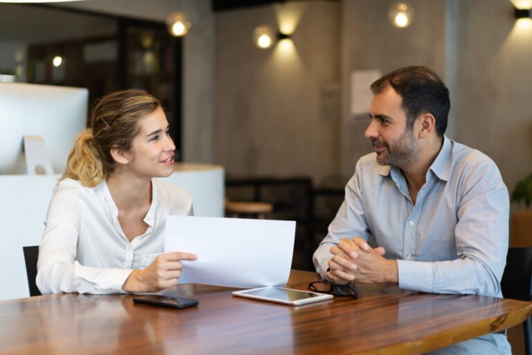 positive-young-employee-showing-report-business-colleague